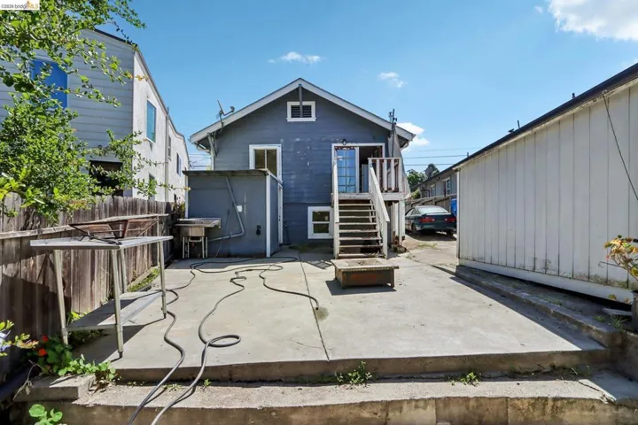 Rear exterior featuring a concrete patio, exterior staircase, and an adjacent auxiliary structure