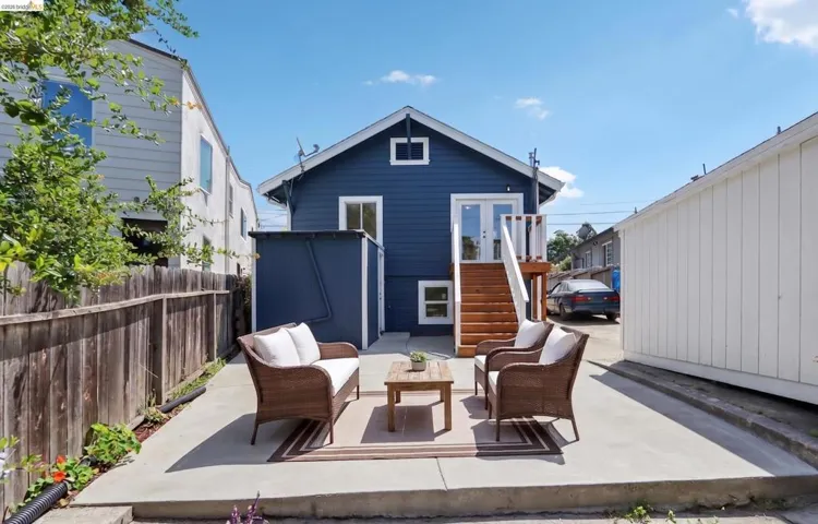 Rear exterior with a concrete patio, wooden privacy fence, and an exterior storage shed. AI-Generated