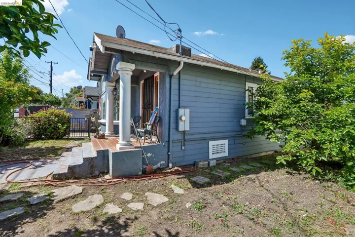 Property exterior featuring blue horizontal siding, a covered porch with white columns, concrete steps, and a decorative metal security door