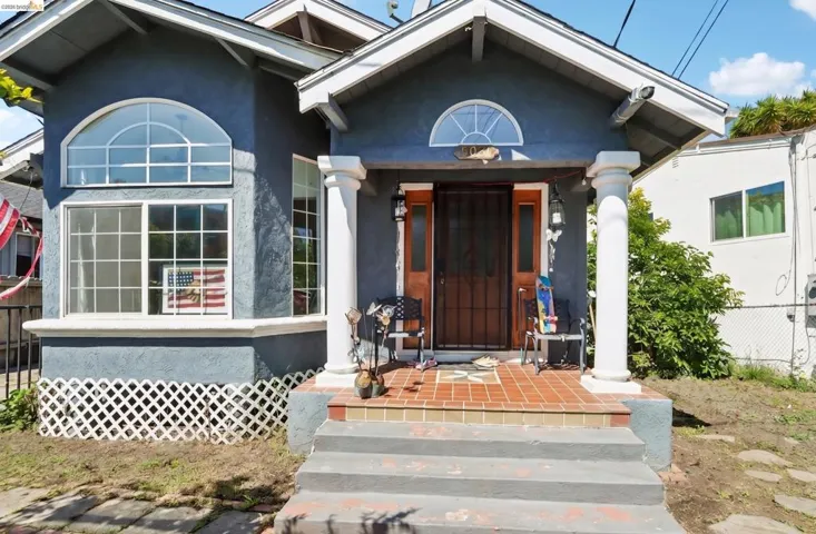Stucco exterior with a columned porch entrance, featuring an arched transom window and a solid wood entry door