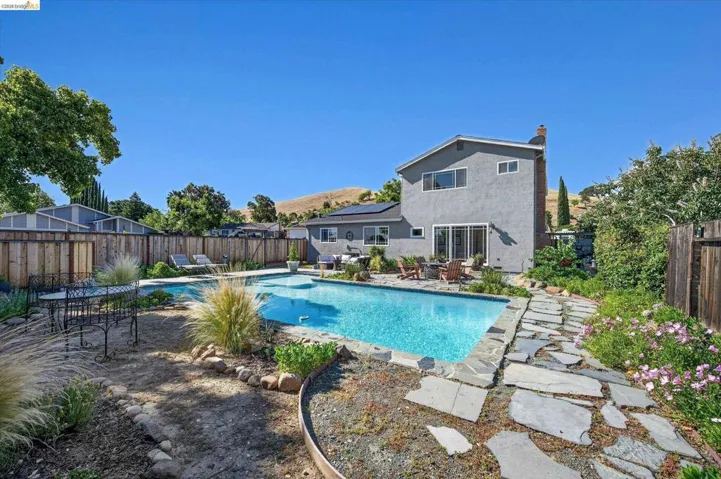 Expansive backyard oasis featuring a rectangular pool, flagstone patio, and mature landscaping