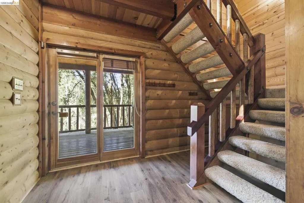 Interior wood staircase with open railing and knotty pine wall detail. Connects multiple levels of the three-story layout.
