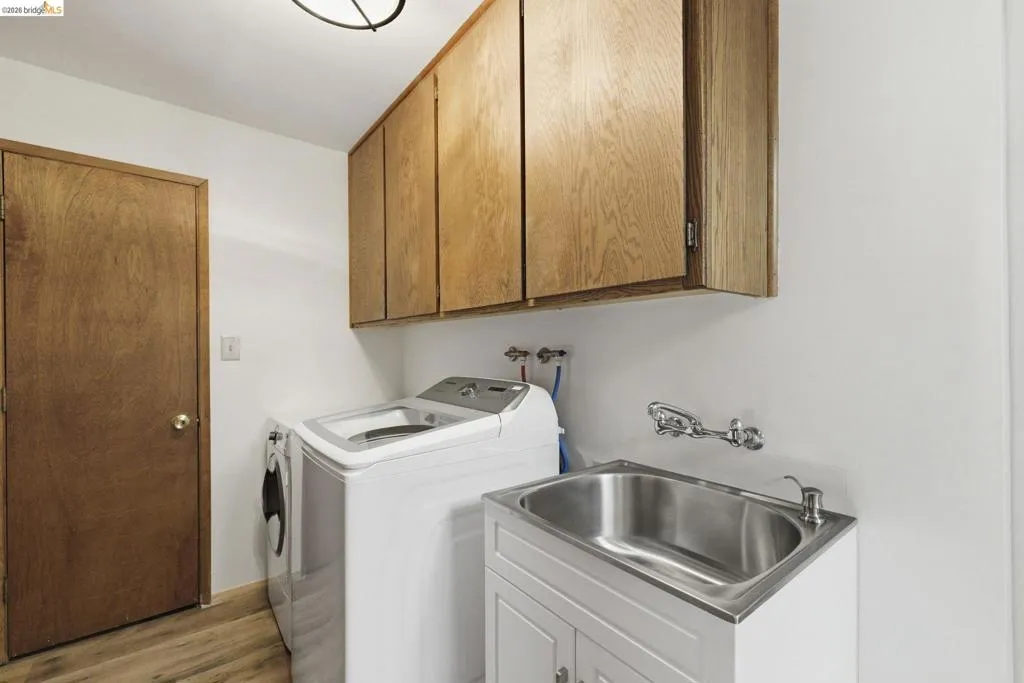Dedicated laundry room with washer and dryer included, utility sink, and upper cabinetry. Wood panel walls consistent with interior finishes.