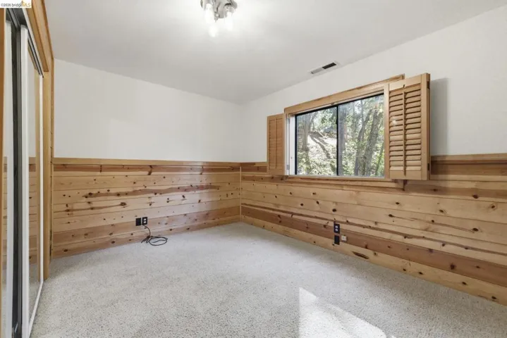 Room with carpet, knotty pine walls, recessed lighting, and window. Flexible use as bedroom, office, or bonus room — direct access from lower level corridor.