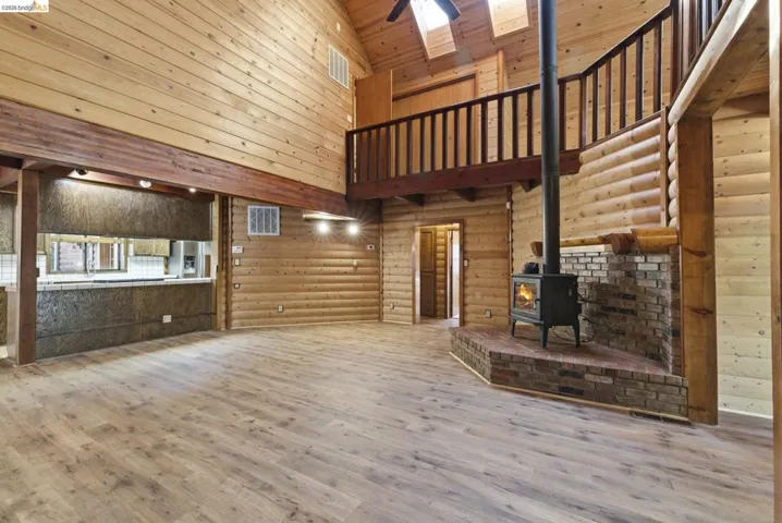 Lower level corridor with wood-look flooring, knotty pine walls, and staircase with wood railing. Shows multi-level layout and access to lower-level rooms.