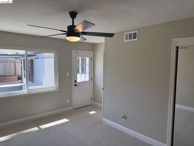 Light-toned wall paint and carpeting, complemented by a modern ceiling fan with integrated lighting
