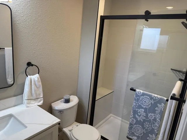 Modern bathroom featuring a glass-enclosed shower with black framing, integrated shower bench, and white subway tile surround
