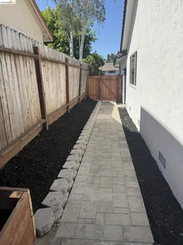 Paver stone walkway bordered by dark ground cover and a low retaining wall