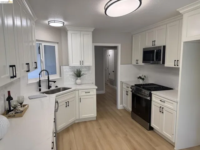 Kitchen featuring white shaker cabinetry with matte black hardware, light-toned wood-finish flooring, white countertops, and a white subway tile backsplash