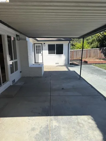Expansive covered patio featuring a corrugated overhead structure and dark support beams