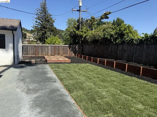 Expansive backyard featuring a lush lawn, gravel patio, and wood privacy fencing