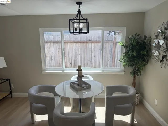 Dining area featuring light wood-finish flooring, neutral-toned walls, and a large window with white trim