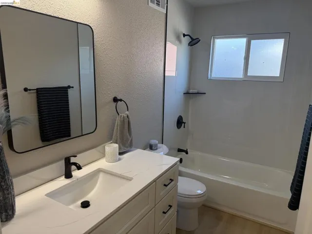 Bathroom featuring a white vanity with an integrated sink, matte black fixtures, and a white bathtub with white subway tile surround