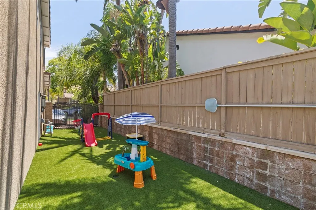Low-maintenance side yard with artificial turf offers additional space for play, pets, and outdoor enjoyment