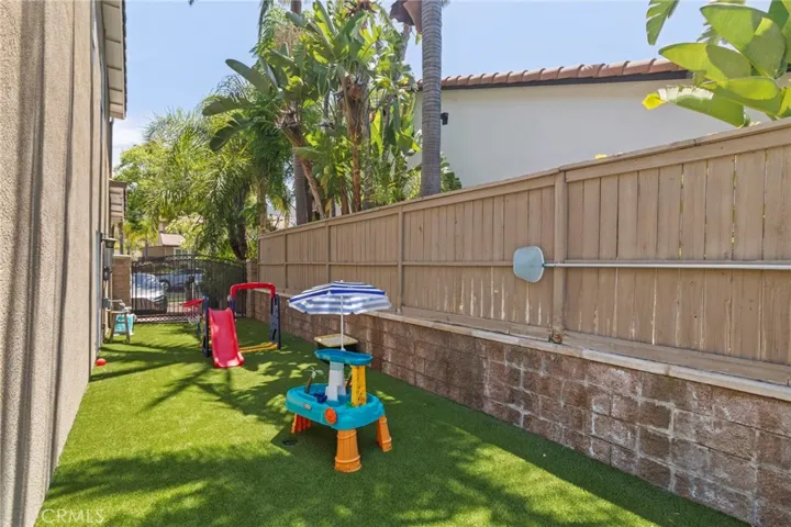 Low-maintenance side yard with artificial turf offers additional space for play, pets, and outdoor enjoyment