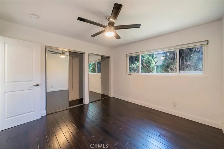 Second bedroom with large mirrored closet doors, ceiling fan and window for breezes