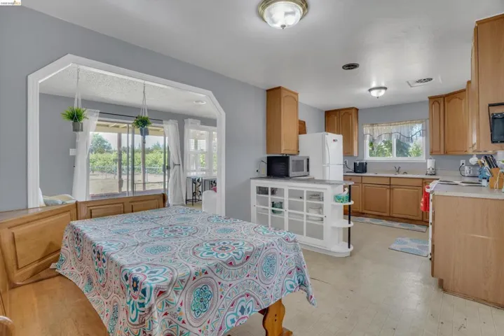 Kitchen featuring wood-finish cabinetry, light countertops, and an integrated white storage island with open shelving