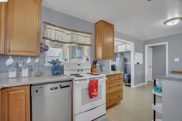 Kitchen featuring wood cabinetry, light-toned countertops, and a white electric range