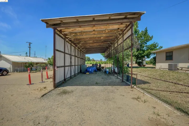 Open-air carport structure with a corrugated metal roof and exposed wood framing