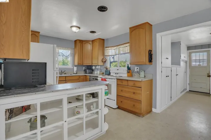Kitchen featuring light wood cabinetry, white appliances, and light-toned flooring