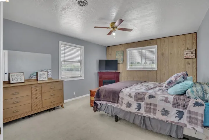 Bedroom featuring light gray painted walls and wood-panel accent wall