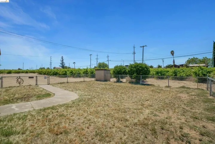Fenced property featuring a concrete pathway, a storage shed, and mature foliage