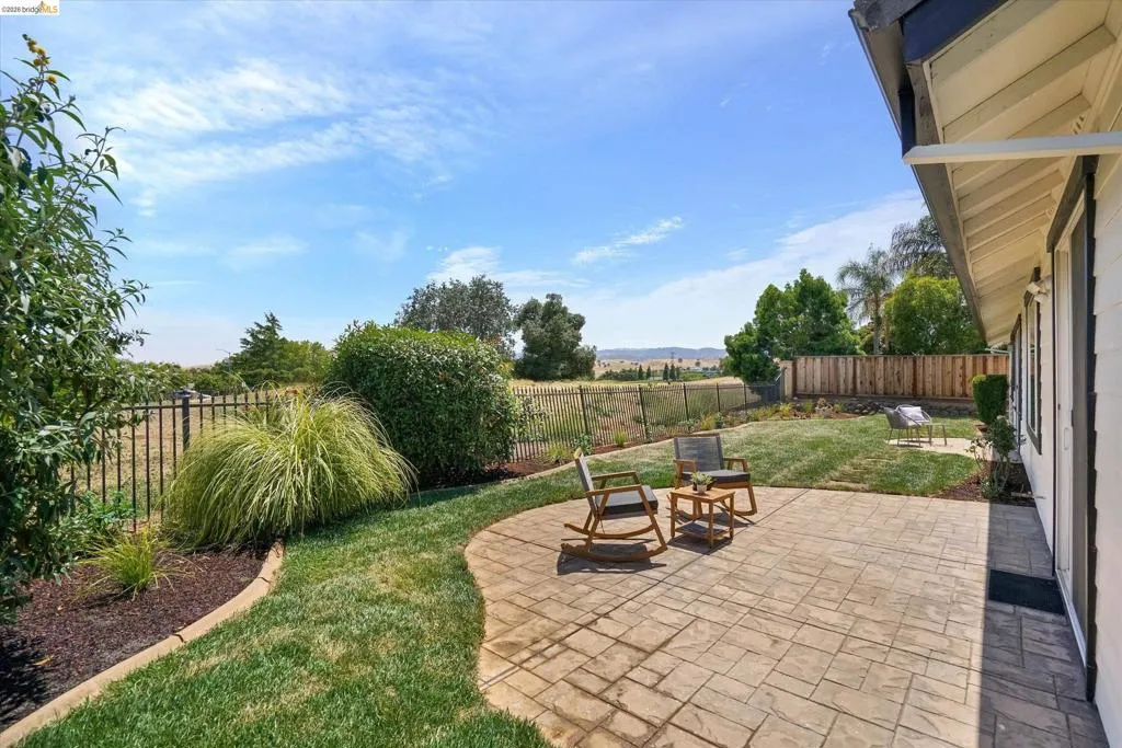 Expansive backyard featuring a stamped concrete patio, manicured lawn, and mature landscaping