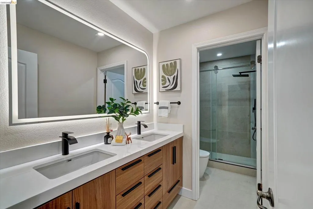 Dual vanity featuring wood-finish cabinetry, integrated rectangular sinks, and matte black fixtures