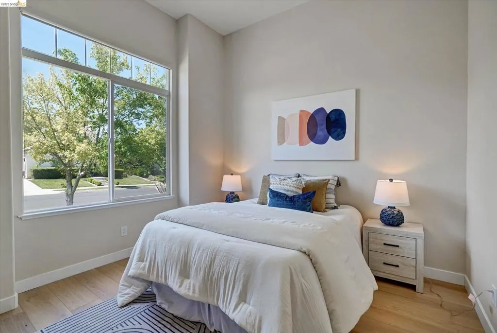Room featuring a large picture window, wood-finish flooring, and neutral wall tones