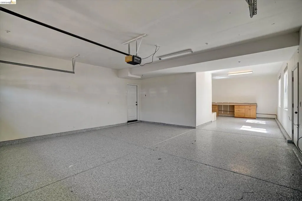 Spacious garage featuring a speckled epoxy floor, white walls, and bright overhead lighting