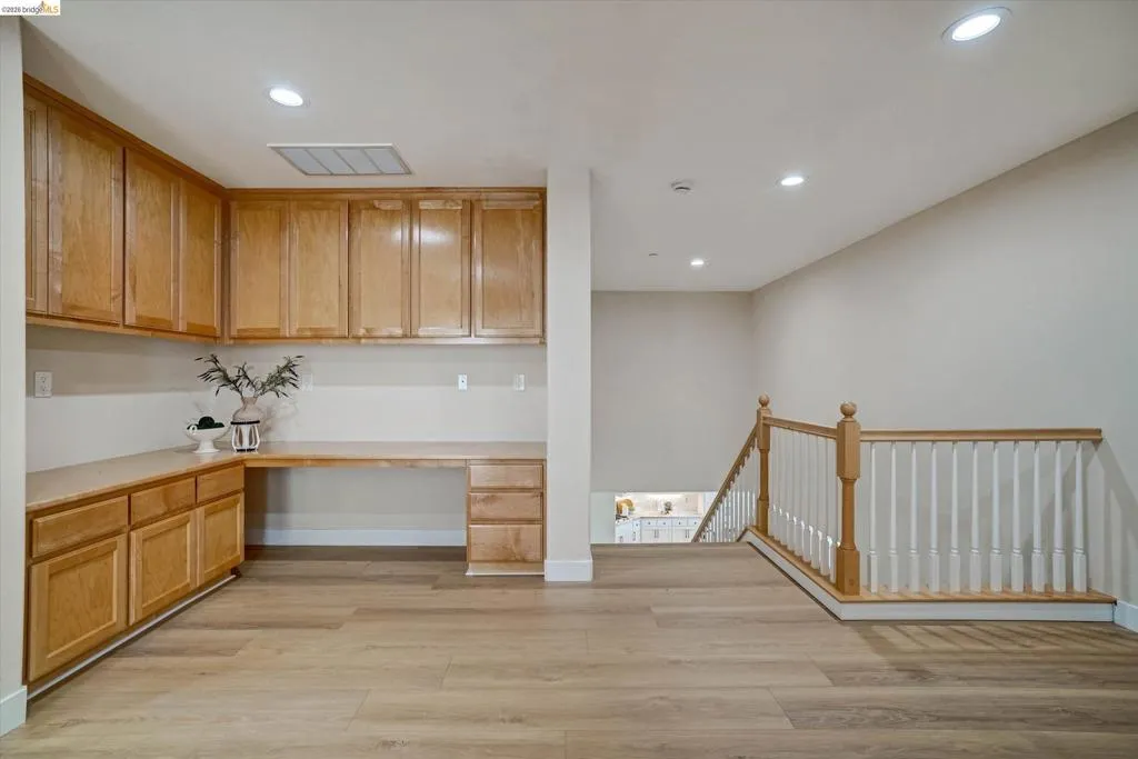 Upper-level landing featuring wood-finish flooring and a staircase with white spindles and a natural wood handrail
