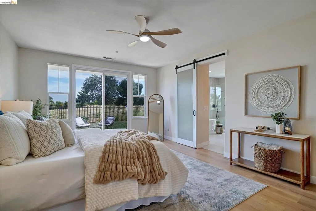 Spacious room featuring wood-finish flooring, a contemporary ceiling fan, and a barn door entry to an adjacent area