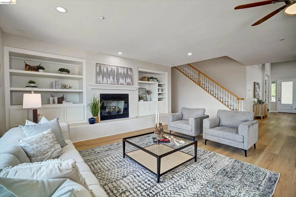 Family room featuring a fireplace with mantle, built-in shelving, wood-finish flooring, recessed lighting