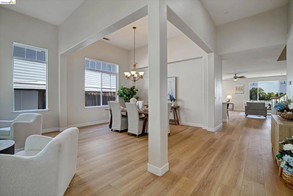 Spacious interior featuring wood-finish flooring, vaulted ceilings, and large windows with horizontal blinds