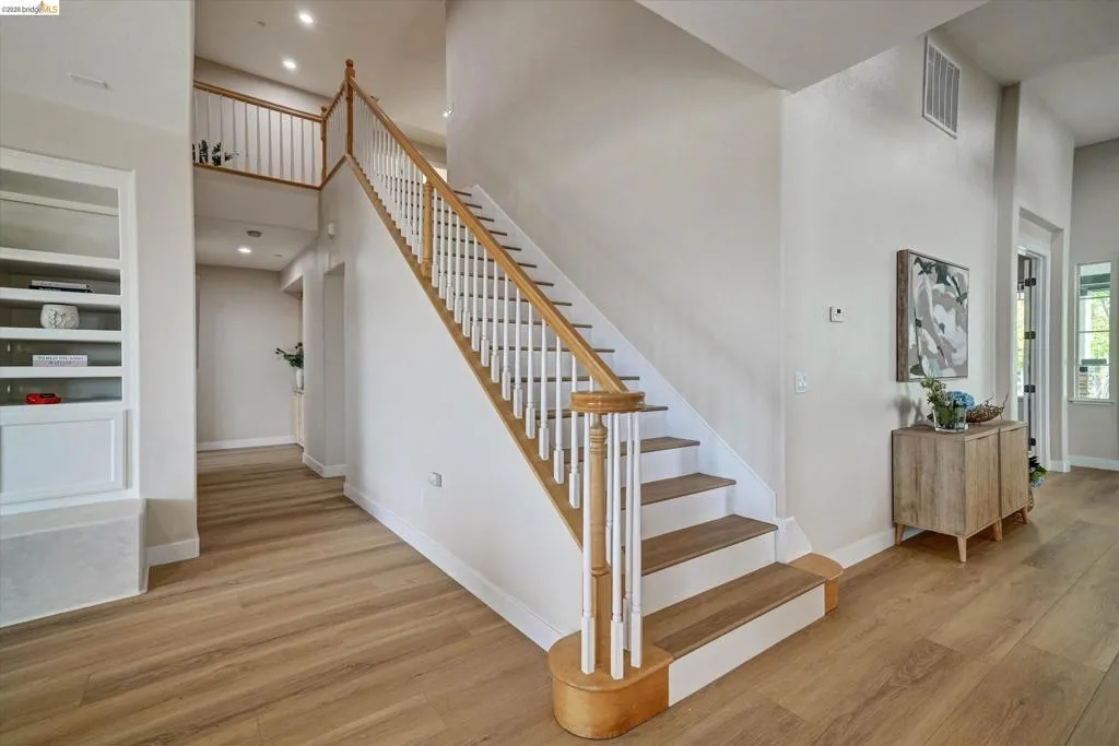 Grand staircase featuring wood-finish treads, white risers, and a white baluster railing with a wood-finish handrail