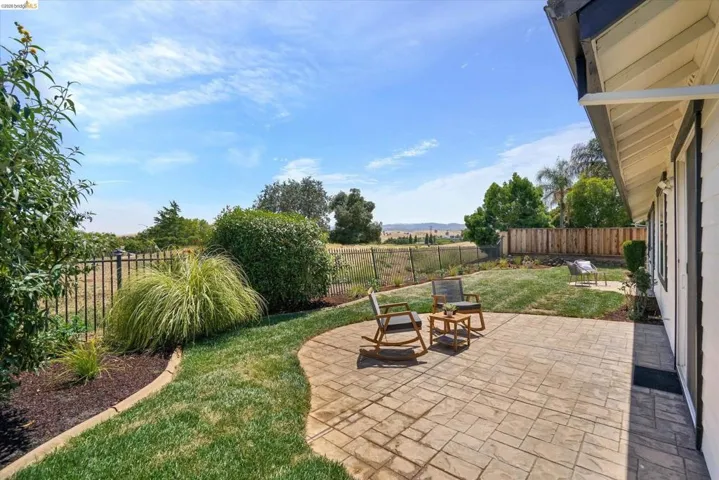 Expansive backyard featuring a stamped concrete patio, manicured lawn, and mature landscaping