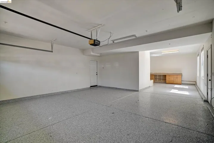 Spacious garage featuring a speckled epoxy floor, white walls, and bright overhead lighting