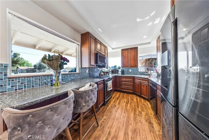 Beautiful appointed kitchen, warm wood cabinetry & breakfast bar seating