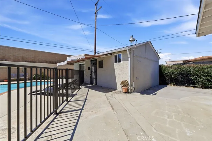 Outdoor living area featuring a pool with safety fencing, covered awning space, and adjacent converted bonus area for flexible use and entertaining.