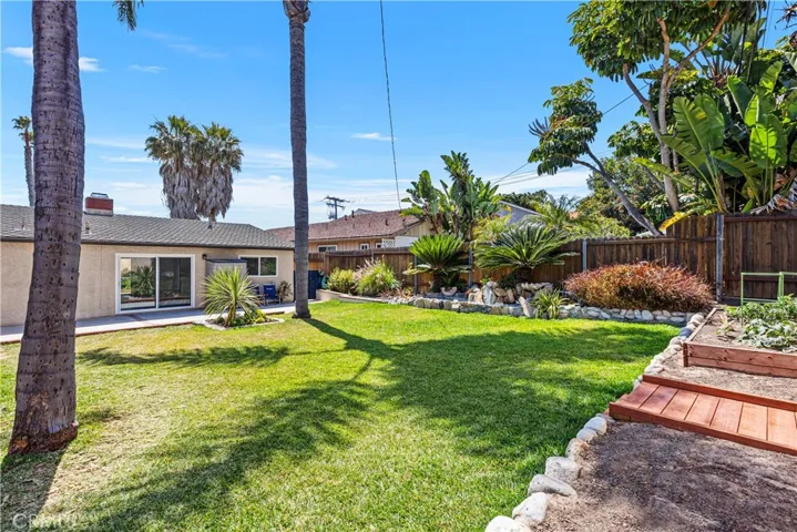Large grassy backyard with palm trees, water feature and gardening area.