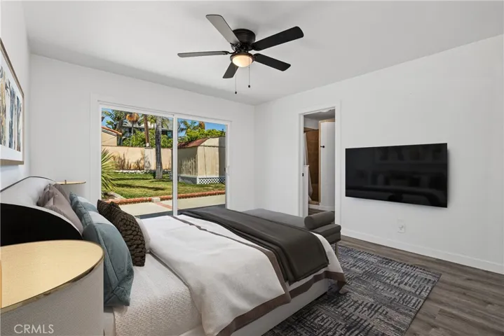 Primary bedroom with new flooring looking out to large grassy backyard. Digitally enhanced photo.