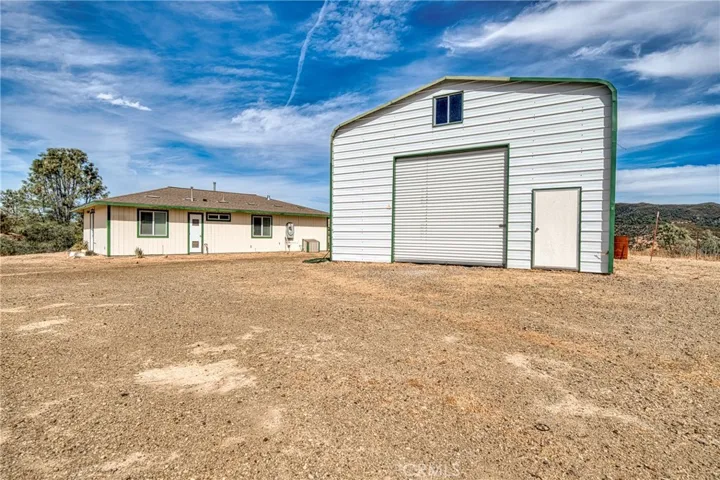 Large metal barn/shop/garage building with side door and a 10 foot rollup entrance.