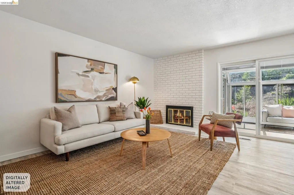Living area featuring a white brick fireplace with a black surround, wood-finish flooring, and a large sliding glass door