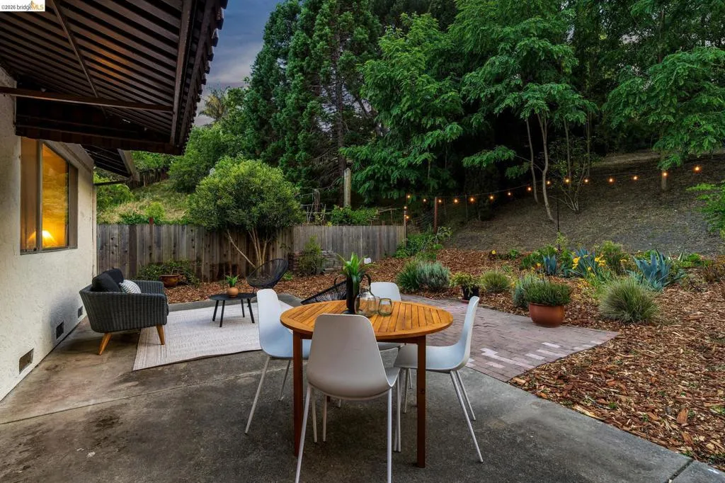 Expansive concrete patio offering a private outdoor living space, surrounded by a mature tree line