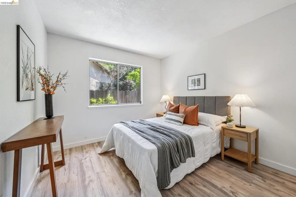 Bedroom with wood-finish flooring, a window offering natural light, and clean white walls