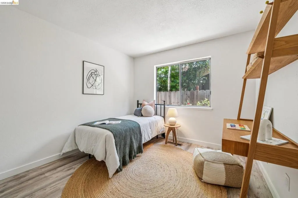 Room featuring wood-finish flooring, white walls, and a large window