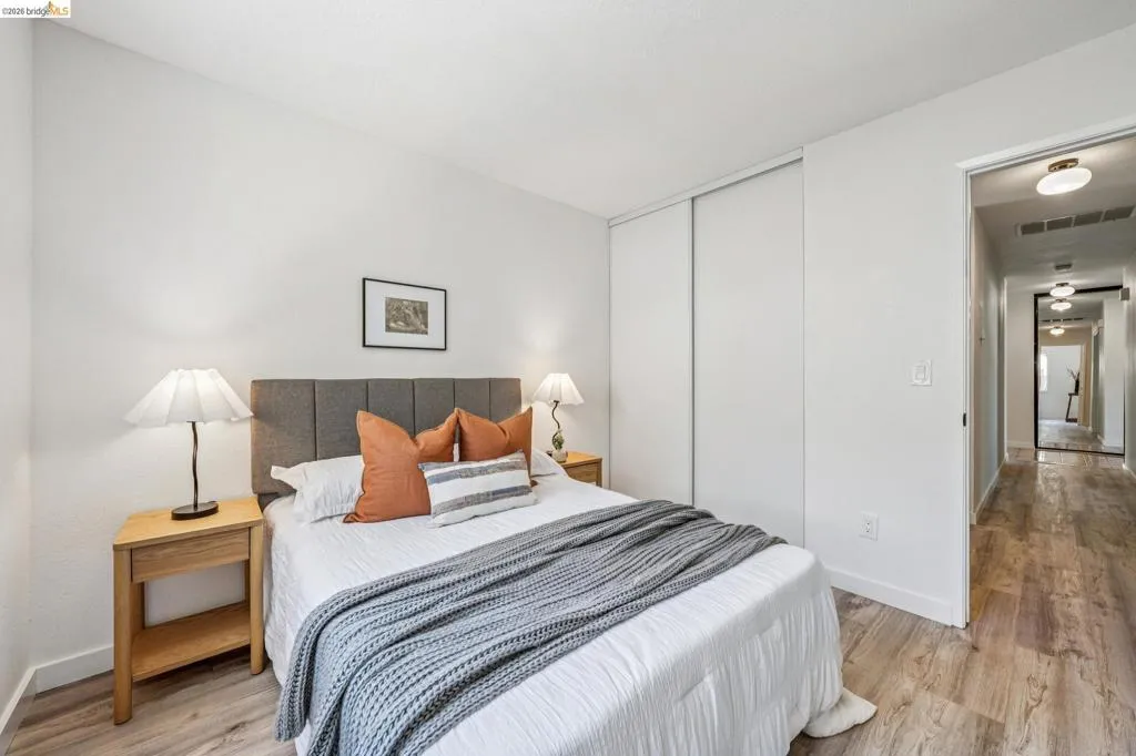 Bedroom featuring light wood-finish flooring, white walls, and a built-in closet with sliding doors