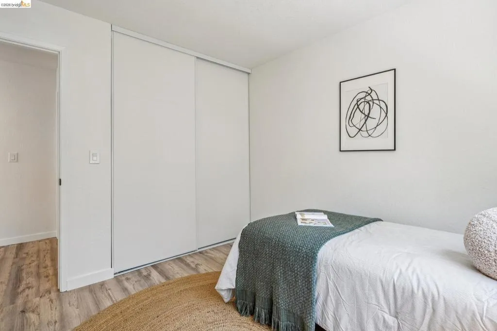 Room featuring clean white walls, wood-finish flooring, and a full-length sliding closet door
