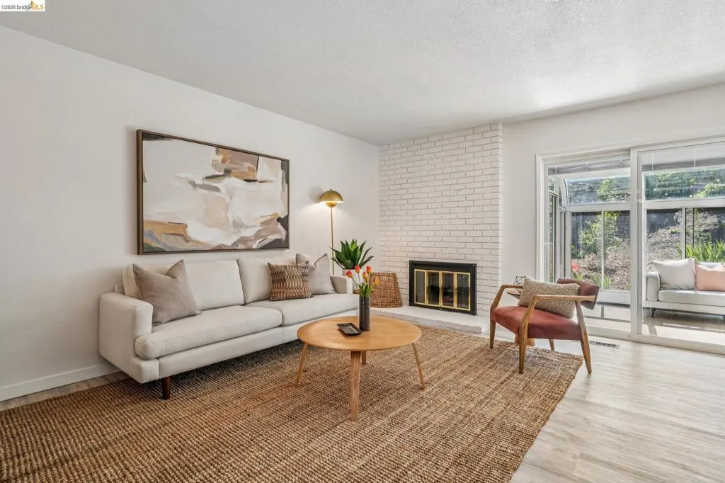 Living area featuring a white brick fireplace, wood-finish flooring, and sliding glass doors