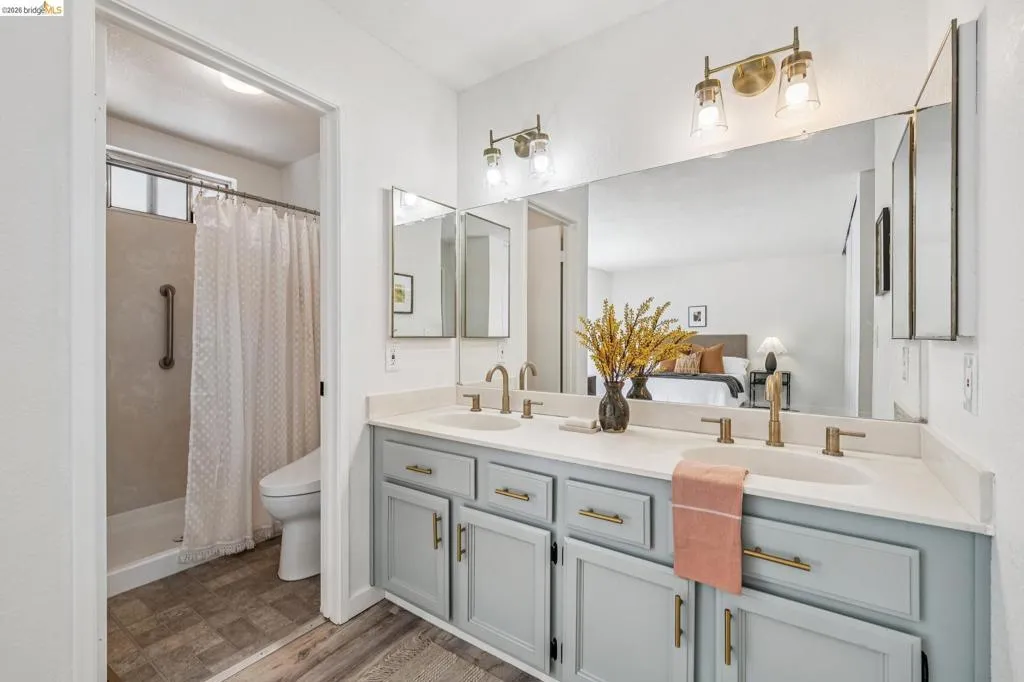 Double vanity with light gray cabinetry and brushed gold hardware, featuring a white countertop and dual undermount sinks